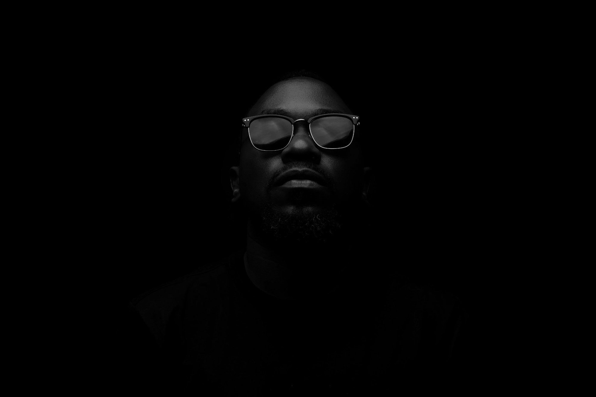 Moustey in sunglasses against a black background
