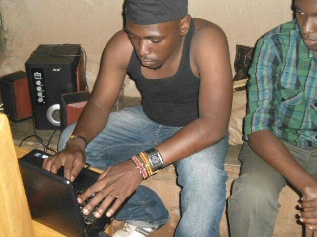 Young Moustey playing music from a laptop in a university hostel room