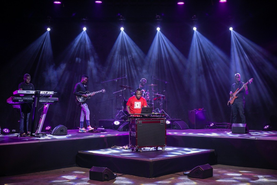 Moustey at the decks centre stage with a live band under purple lights