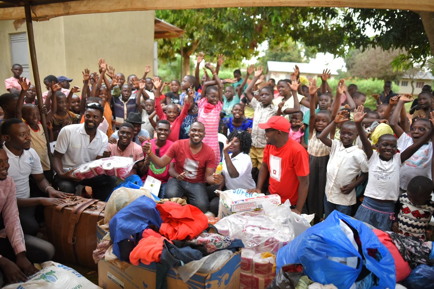 Moustey and the Real Deejays and Clicks of Hope team with children and donated supplies at an orphans' home in Iganga