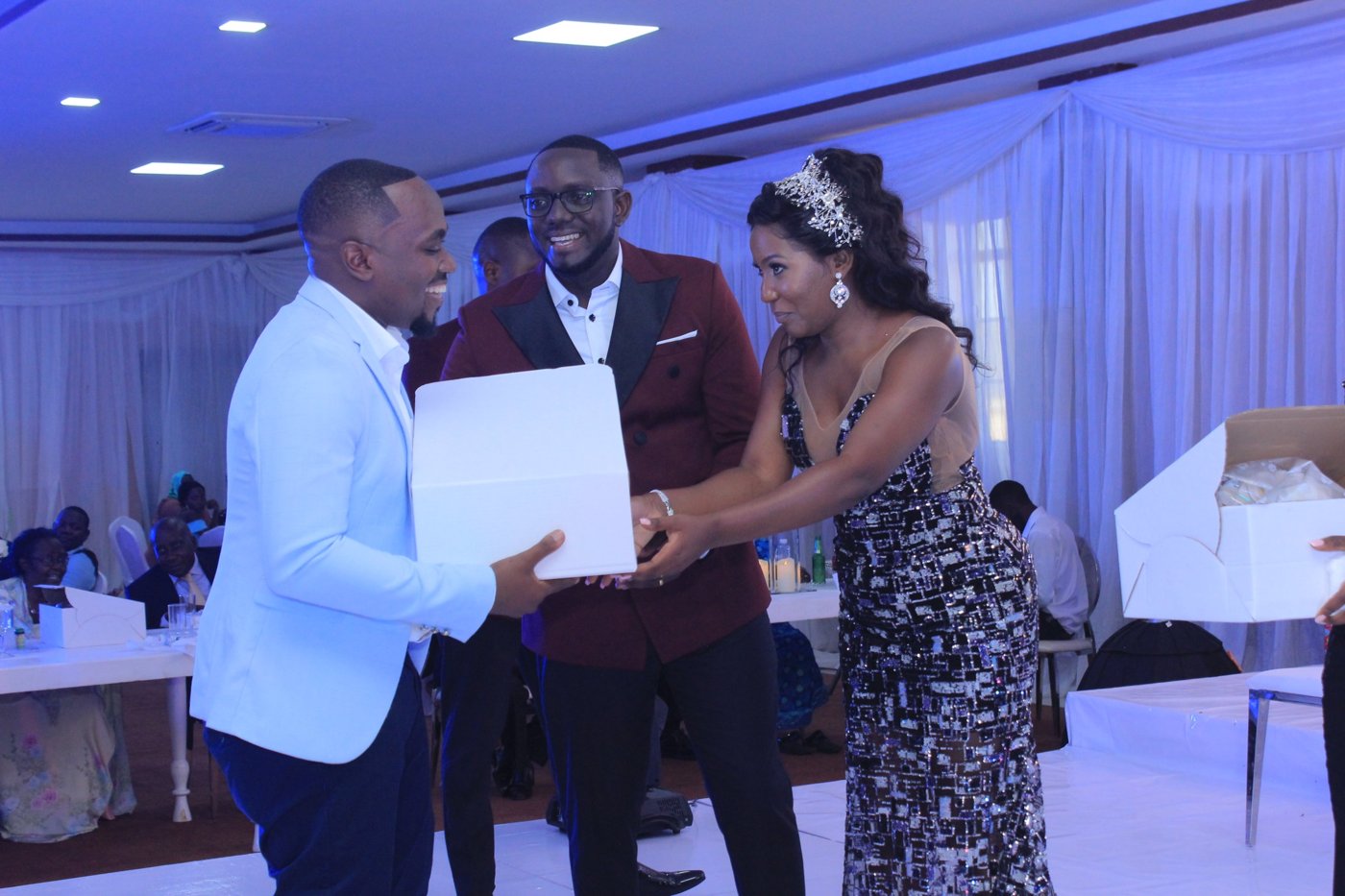 The bride and groom handing Moustey a box of wedding cake on the dance floor